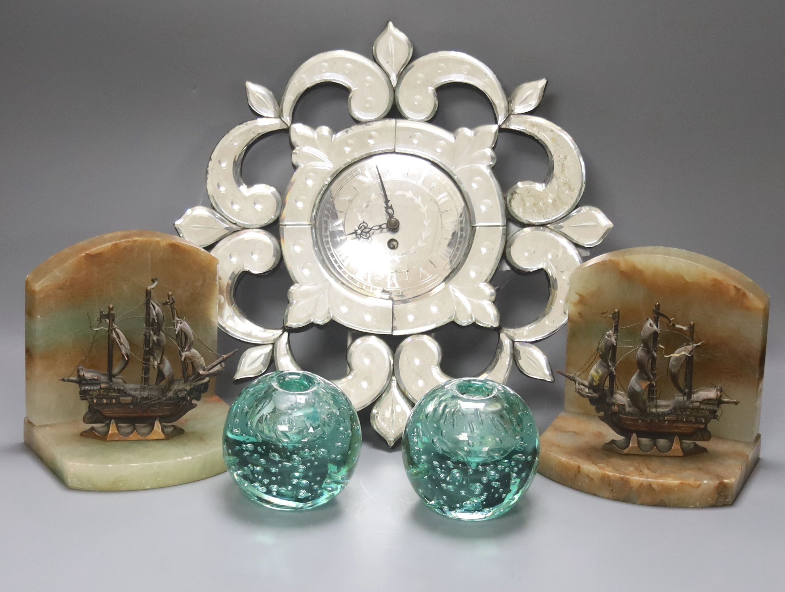 A small Venetian mirrored glass wall clock and a pair of green glass ‘candleholder’ dumps and a pair of ship bookends 33cm
